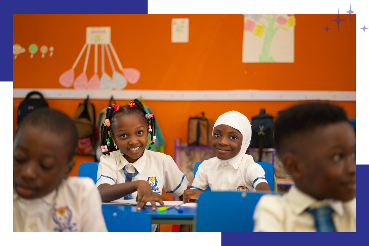 Lower primary students smiling at desks in orange classroom