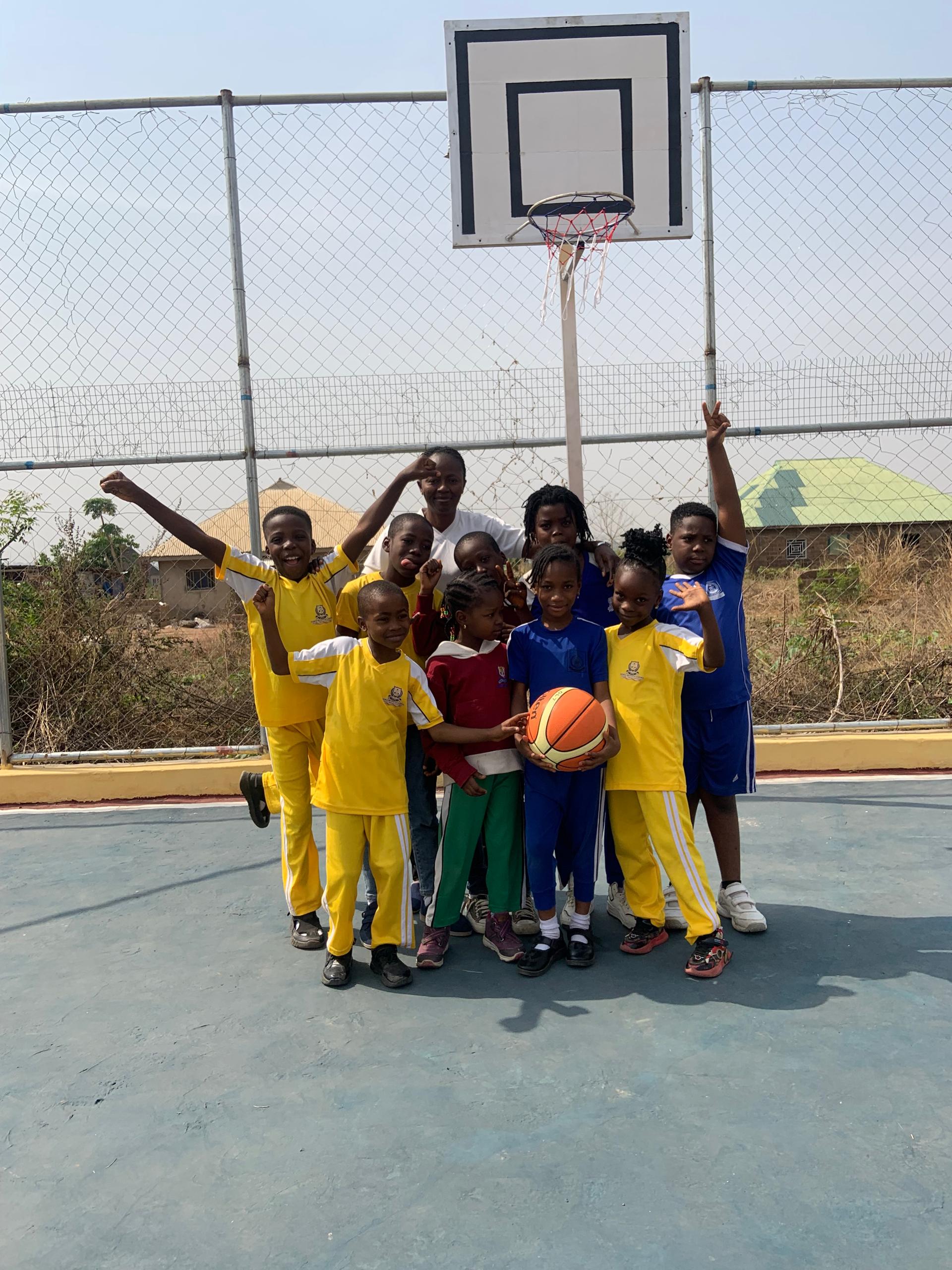 Noble Brains Academy basketball team and coach under the hoop on sports arena