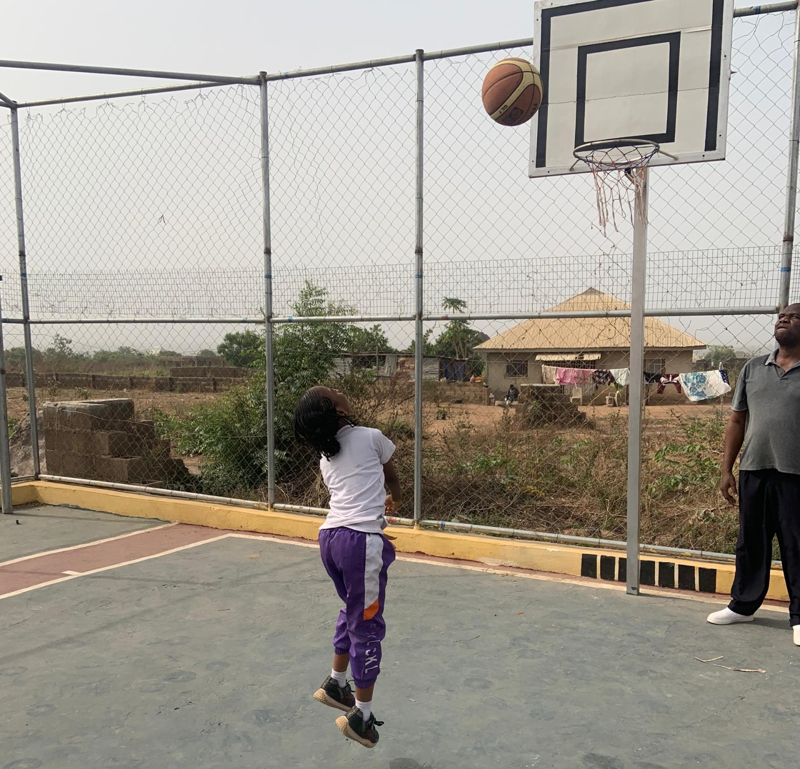 Female pupil leaping to shoot basketball with coach
